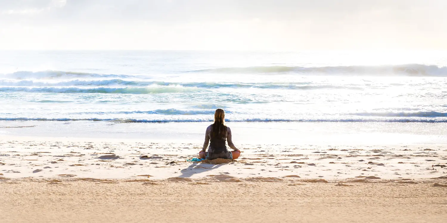 Frau praktiziert Meditation am Strand